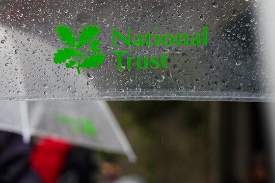 The National Trust organisational logo printed clearly on a transparent umbrella during rainy weather outdoors in the Lake District England