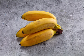 Grey stone surface, yellow ripe bananas, fruit bunch © Andrei Starostin