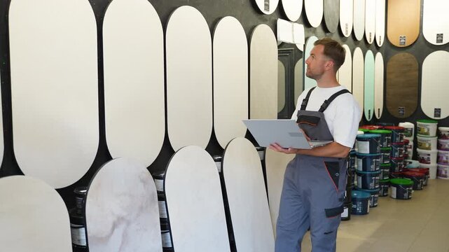 Warehouse worker using laptop for inventory in hardware store