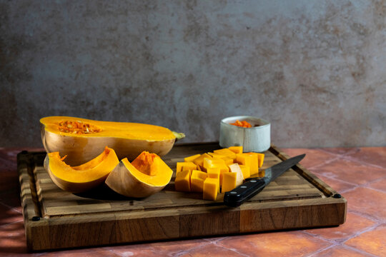 Butternut squash in pieces on a wood cutting board 