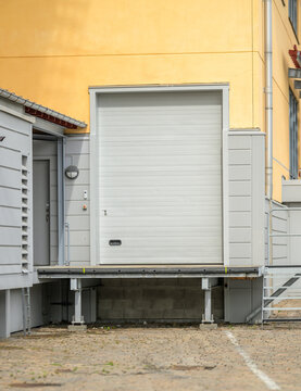 Industrial loading door on yellow waterfront building exterior.