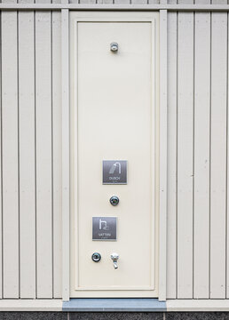 Outdoor shower and water service panel on wooden building wall.