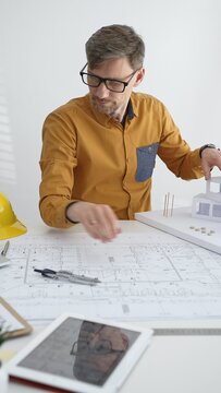 Architect developing building design with blueprint and architectural model, planning construction project, drawing plans with ruler, working on housing layout