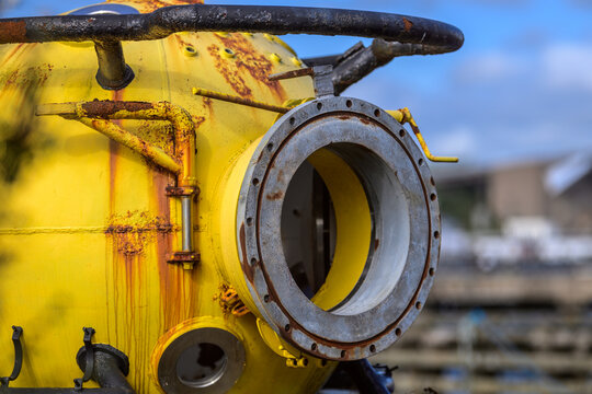 Weathered yellow industrial pressure vessel with open flanged access hatch.