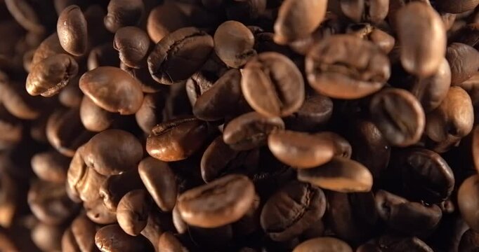 Roasted coffee beans falling in super slow motion 1000 fps macro top view