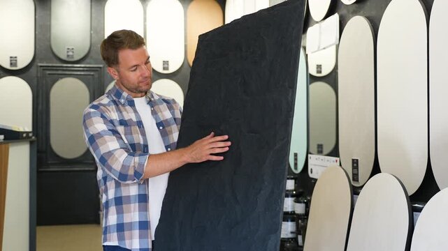Designer selecting large black slate panel in showroom