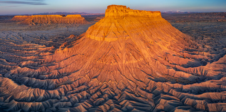 Factory Butte rocky textured standing above the desert floor at sunrise