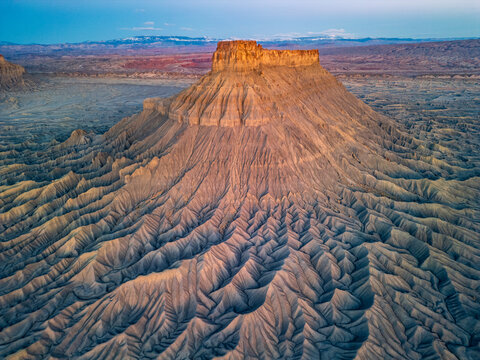 Factory Butte rocky textured standing above the desert floor at sunrise