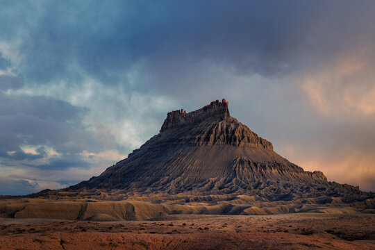 Factory Butte rocky textured standing above the desert floor at sunset