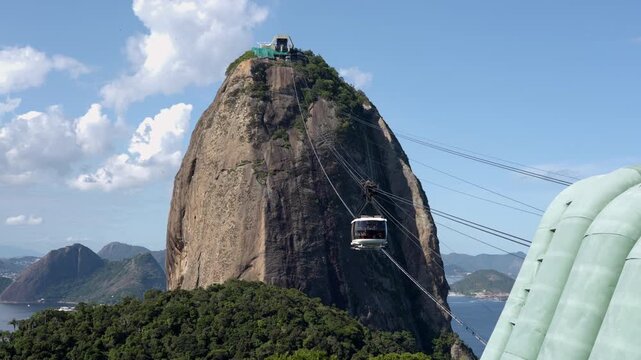 Cable car descending from Sugarloaf Mountain toward Morro da Urca on a sunny day, Rio de Janeiro, Brazil.