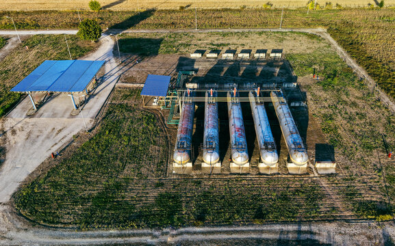Aerial view of an old gas station featuring five large cylindrical gas tanks and a blue-roofed canopy situated in a rural landscape in Debeljaca, Vojvodina, Serbia.