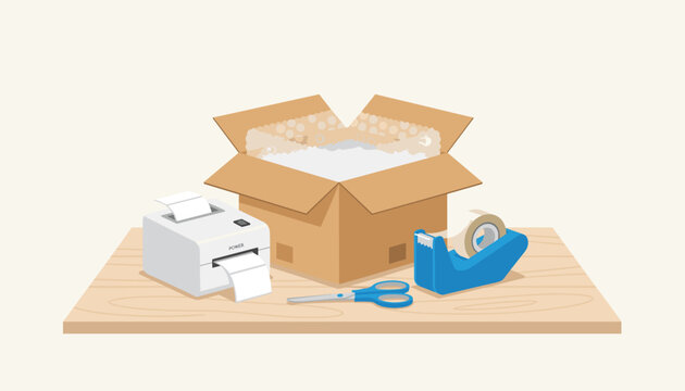 Packing station displays an open cardboard shipping box filled with bubble wrap beside a thermal label printer tape and scissors.