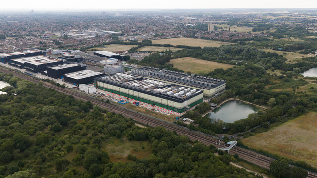 Aerial view of the NTT LON1B Data Centre industrial facility surrounded by greenery, railway tracks, and ponds in Dagenham, England, United Kingdom.