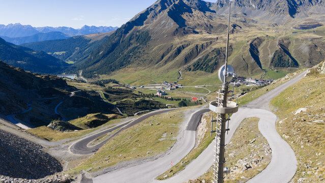 Aerial view of Finstertaler-Damm Denkmal and the winding mountain roads of the alpine landscape in Silz, Tirol, Austria.