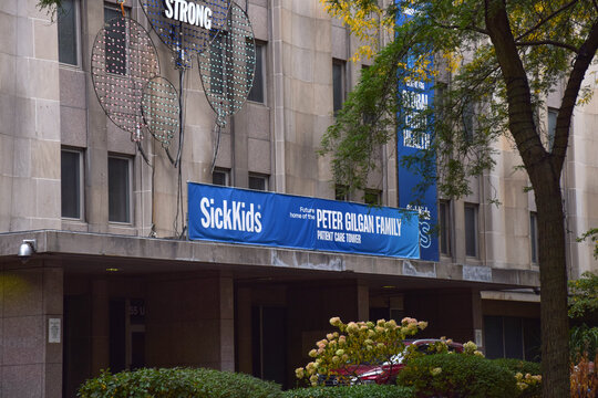 Exterior view of the Hospital for Sick Children featuring a blue banner announcing the future Peter Gilgan Family Patient Care Tower, September 2026