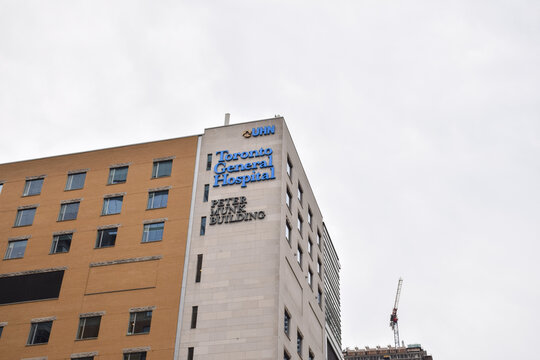 Low angle exterior shot of the Toronto General Hospital Peter Munk Building corner showing UHN logo and hospital signage against the sky, September 2026