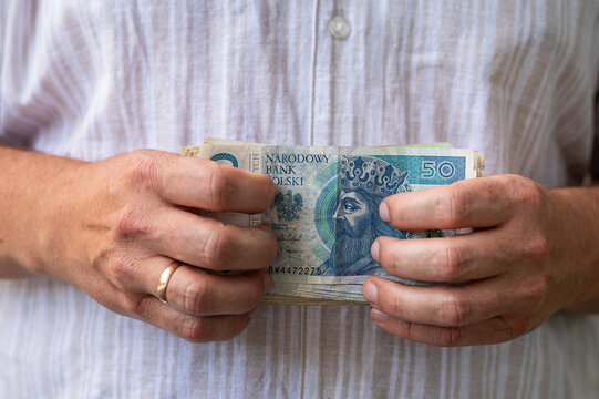 Close up of Man Hands Holding Fan of Polish Zloty Banknotes for Income and Savings Concept