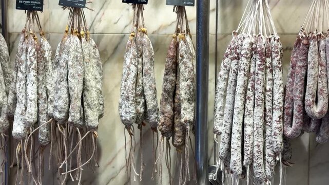 Rows of dry cured sausages hanging in a deli shop, traditional fuet and salami with white mold casing on display, gourmet charcuterie and tapas concept