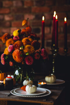Beautiful elegant autumn table setting for thanksgiving family dinner or wedding with dahlias. Orange pumpkin, floral centrepiece. Cozy fall home atmosphere. Wineglass, romantic marriage proposal