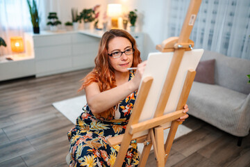 Redhead woman creating art on canvas at home studio © Jelena