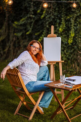 Woman artist painting outdoors in her garden creating art © Jelena
