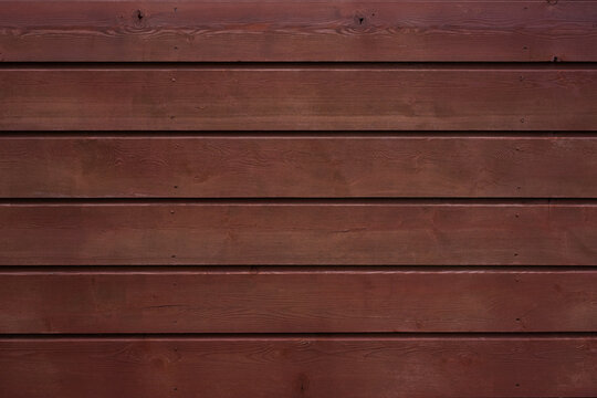 Brown painted wooden fence with overlapping horizontal panels and visible grain