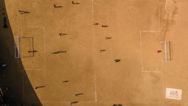 Aerial view of a soccer match being played on a dusty field in Matheran, Maharashtra, India.