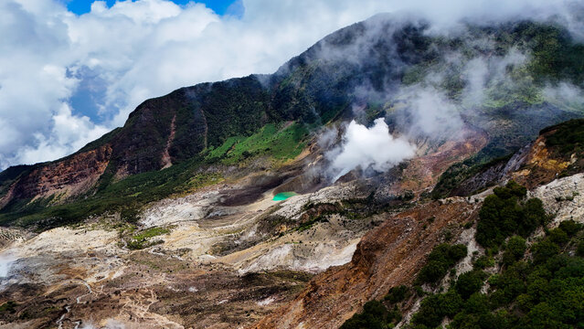 Aerial view of Mount Papandayan with its volcanic crater, steaming sulfur vents, and lush green mountain slopes in Garut, West Java, Indonesia.