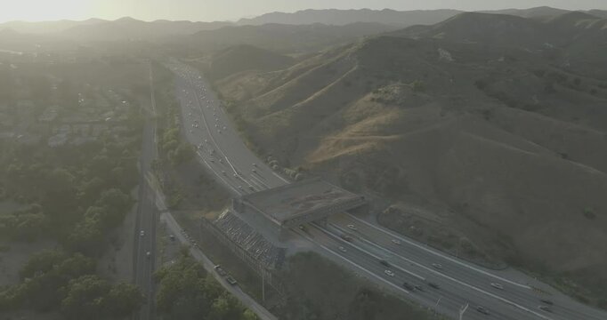 Aerial view of highway lanes passing under bridge among dry hills