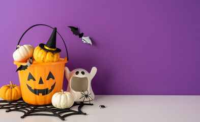 Happy Halloween decorations with jack-o-lantern bucket, ghost and pumpkin display on purple...