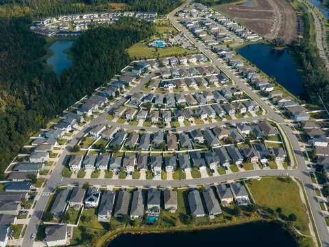 Aerial view of a residential community featuring rows of identical suburban houses, manicured lawns, and winding streets in Jacksonville, Florida, United States.