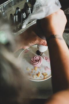 cupcake frosting, pink icing, pastry decorating, frosting technique, cake decorating, cupcake preparation, piping bag, buttercream rose, dessert making, baking beh