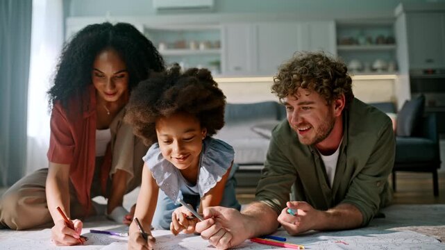 Girl coloring giant poster floor parents. Happy family drawing markers home.