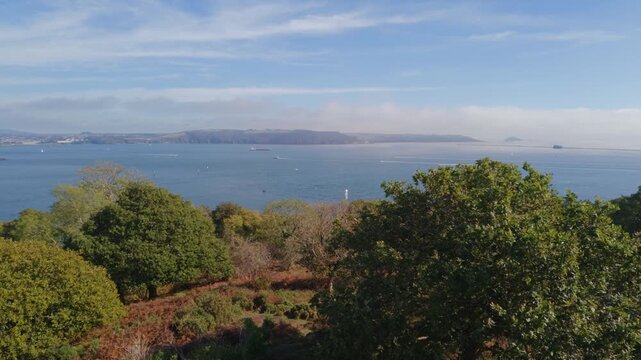 A static shot of coastal landscape viewed from high ground. The view looks east across a wide estuary towards Haybrook Bay, with numerous boats dotting the water and distant landmasses.