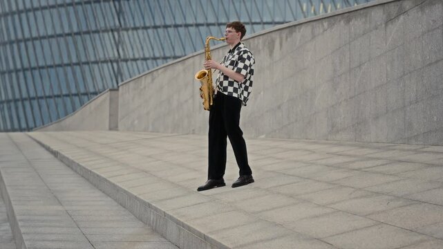 Caucasian young adult playing saxophone on urban city steps. Visual asset suited for music education, creative arts and youth culture advertising