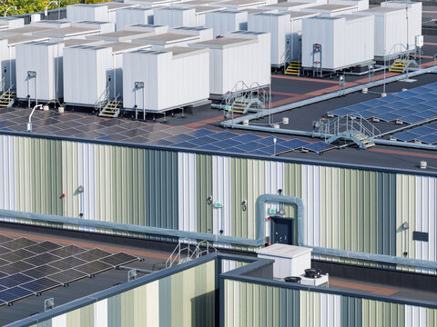 Aerial view of a data center rooftop featuring numerous HVAC units, rows of solar panels, and industrial metal cladding in the United Kingdom.