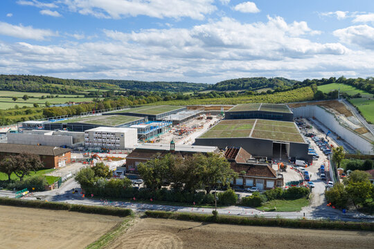 Aerial view of a large data center construction site featuring modern buildings with green roofs, surrounded by rural landscape and rolling hills in the United Kingdom.