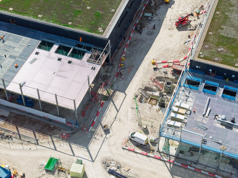 Aerial view of a data center construction site featuring steel frameworks, heavy machinery, and partially completed green roofs in the United Kingdom.