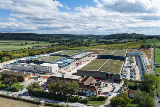 Aerial view of a large data center construction site featuring modern buildings with green roofs, surrounded by rolling hills and rural landscape in the United Kingdom.