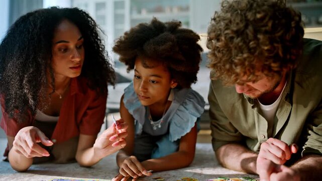 Multiethnic family lying floor solving jigsaw puzzle. Close up hands playing.