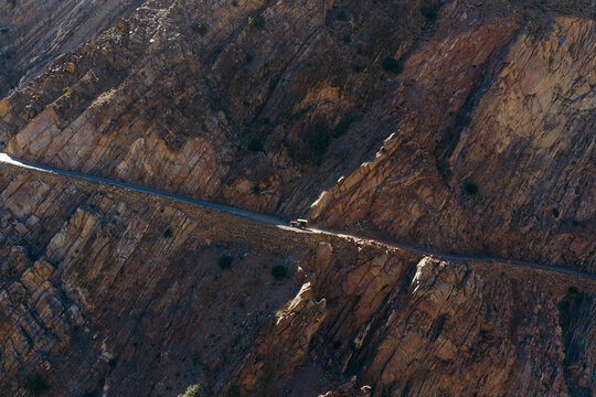 Aerial view of a jeep driving along the narrow and winding Fairy Meadows Road carved into the steep, rugged rock face of the mountains in Fairy Meadows, Balochistan, Pakistan.