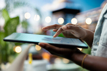 Person uses a smart home gardening app on a tablet from a rooftop terrace, configuring irrigation settings for automated plant care and container gardening. © DC Studio
