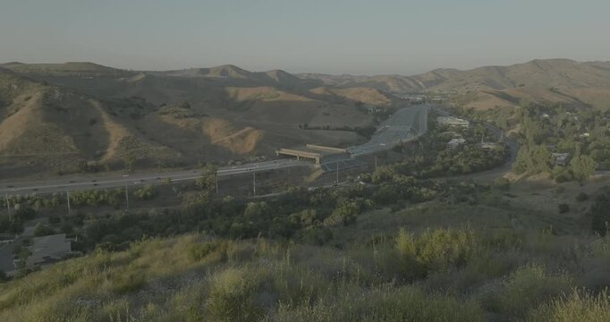 Aerial view of highway winding through golden hills and green brush