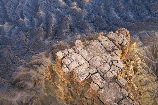 Aerial view of Factory Butte rising above the rugged, eroded badlands of the Mancos Shale in Wayne County, Utah, United States.