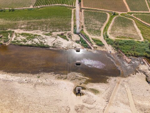 Aerial view of the Breede River crossing with bridge piers and surrounding agricultural vineyards in Bonnievale, Western Cape, South Africa.