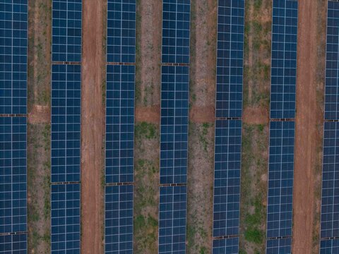 Aerial view of solar panels arranged in long rows with dirt access paths in a solar farm in Bonnievale, Western Cape, South Africa.
