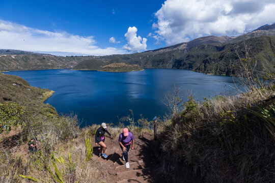Athletes participating in a outdoor trail running competition around the scenic Cuicocha volcanic lake crater on a bright sunny day