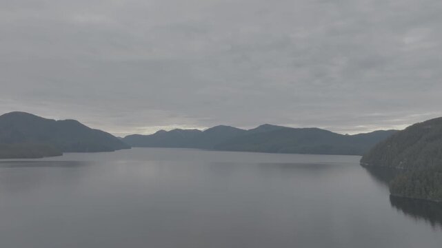 Aerial view of serene fjord with forested headland and cloudy sky