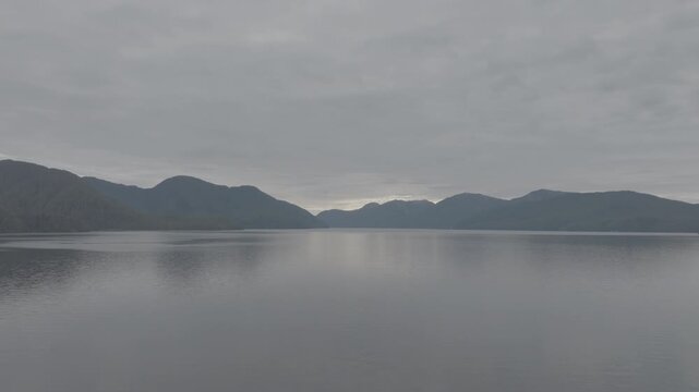 Wide aerial view of quiet fjord water and far mountain range