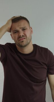 Man looks toward the camera with an exasperated expression and a hand near his head, representing frustration and annoyance